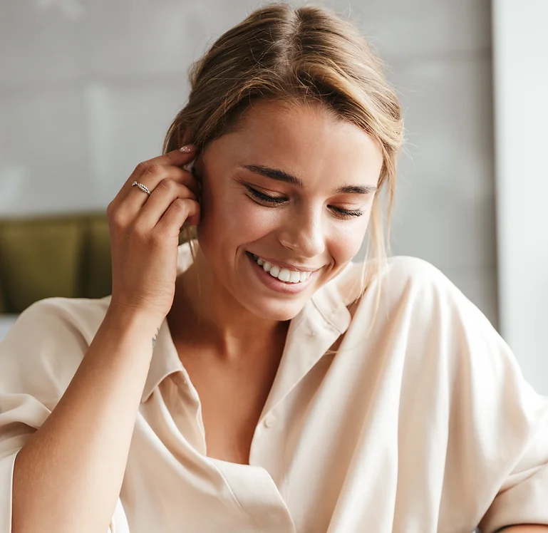 A young woman smiling while listening to her earphones, displaying a beautiful composite bonding smile in Hampstead.