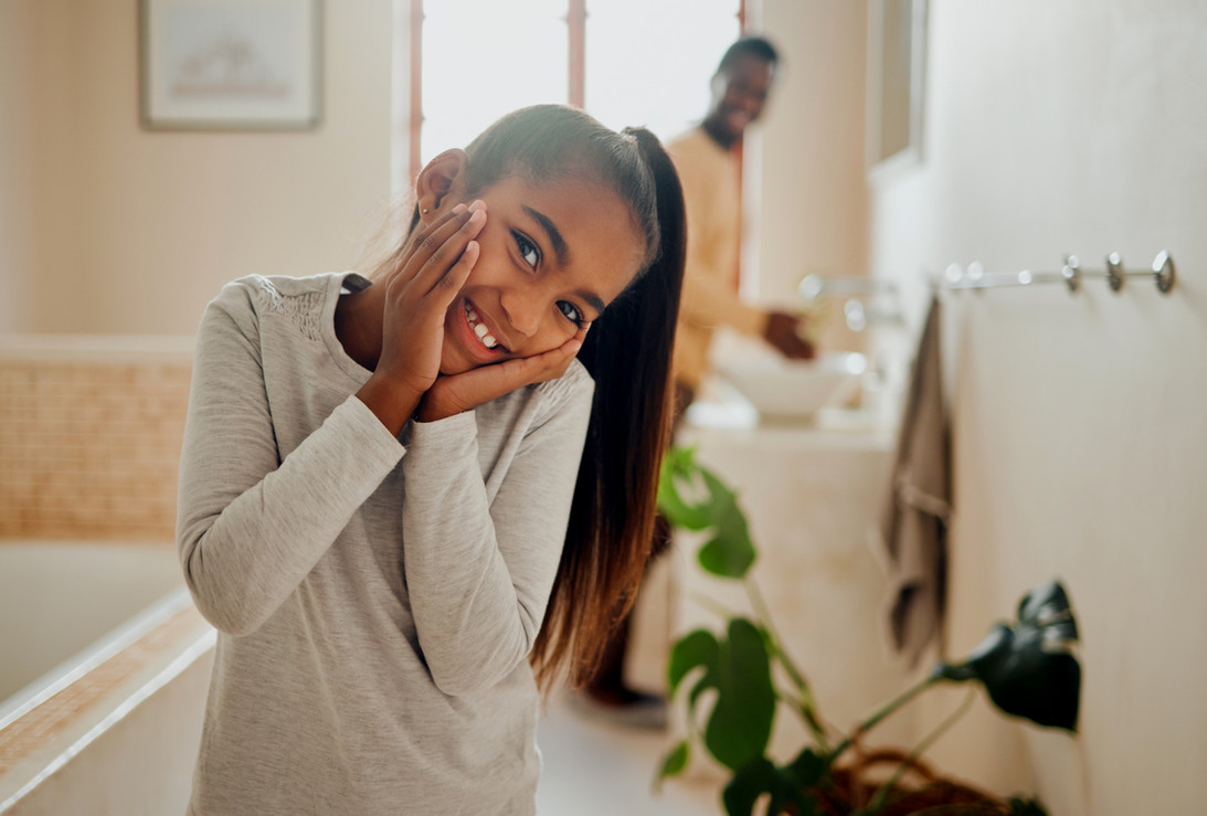 A young girl is smiling while standing in the bathroom after her dentist appointment in Hampstead.